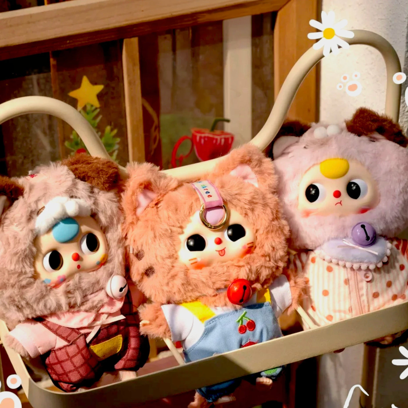 Three plush kitten keychain figures with different outfits, sitting in a display carrier