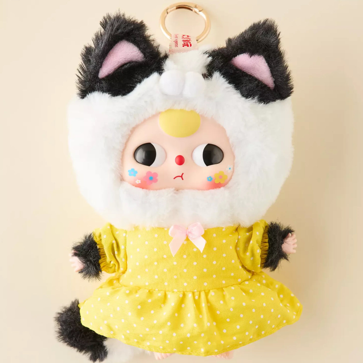 Cat keychain plush with white furry hood, black ear tufts, and yellow dotted dress; ring
