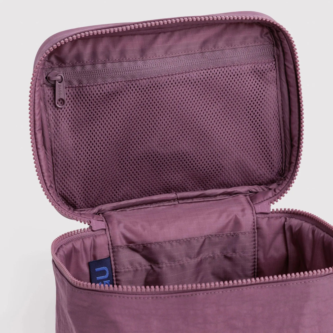 Wild plum cosmetic case interior view with mesh pocket and zipper pull, blue tag