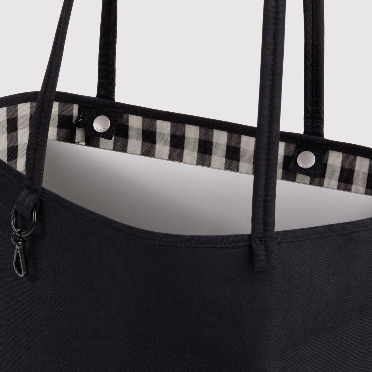 Nylon tote top detail: black handles, gingham lining, and snap buttons