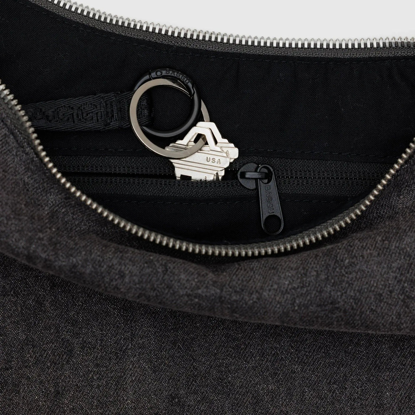 Baggu crescent bag interior with top zipper, metal ring and logo patch