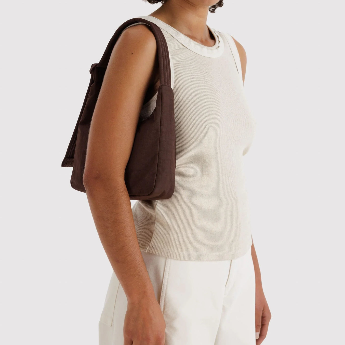 Baggu mini nylon shoulder bag in coffee brown, worn on shoulder with side profile