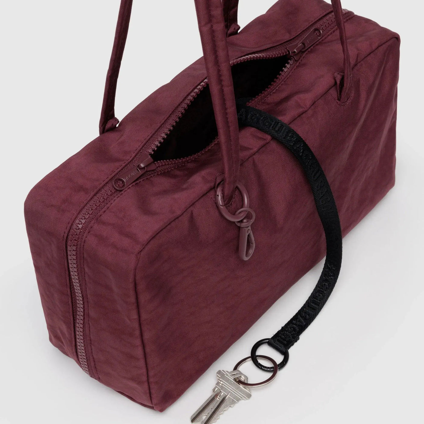 Mahogany nylon bowler bag close-up showing top zipper, key clip, and rings
