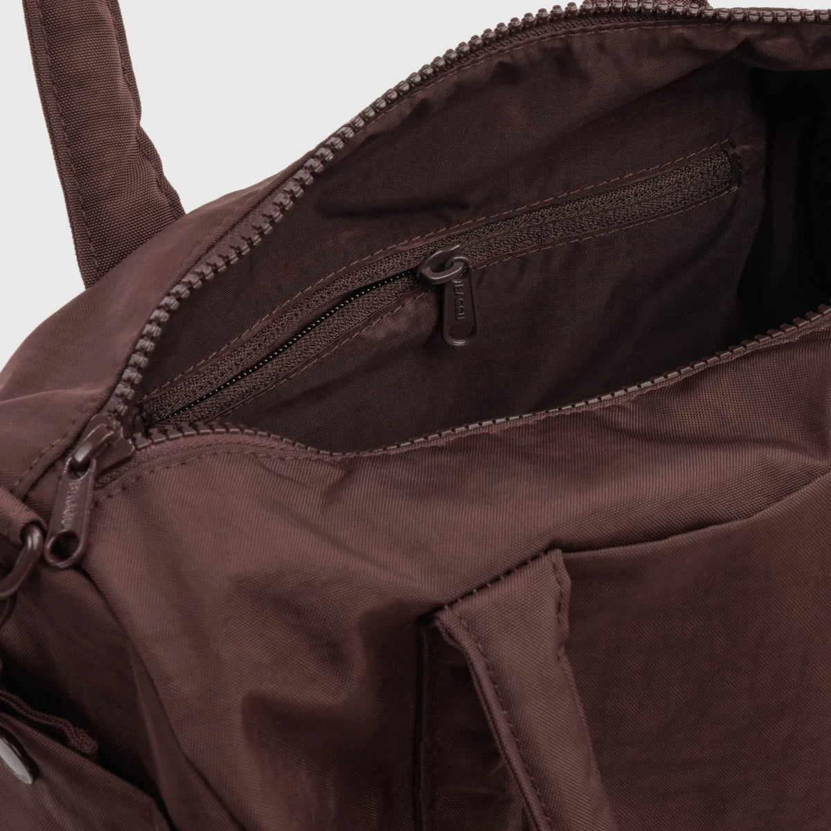 Coffee-brown duffle bag interior with zippered pocket and stitched seams