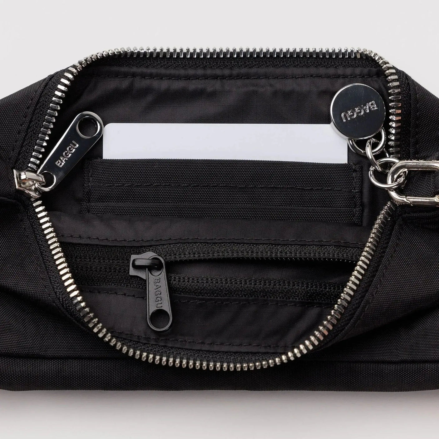 Black nylon pochette interior with zip opening, inner slip pockets, metal hardware