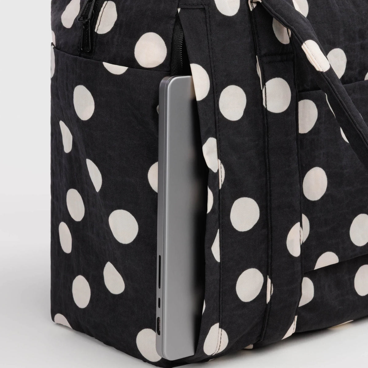Black polka-dot tote bag with cream dots, zipper panel and carry-on sleeve