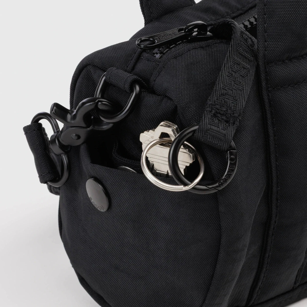 Black nylon duffle bag hardware detail with metal rings and strap clips