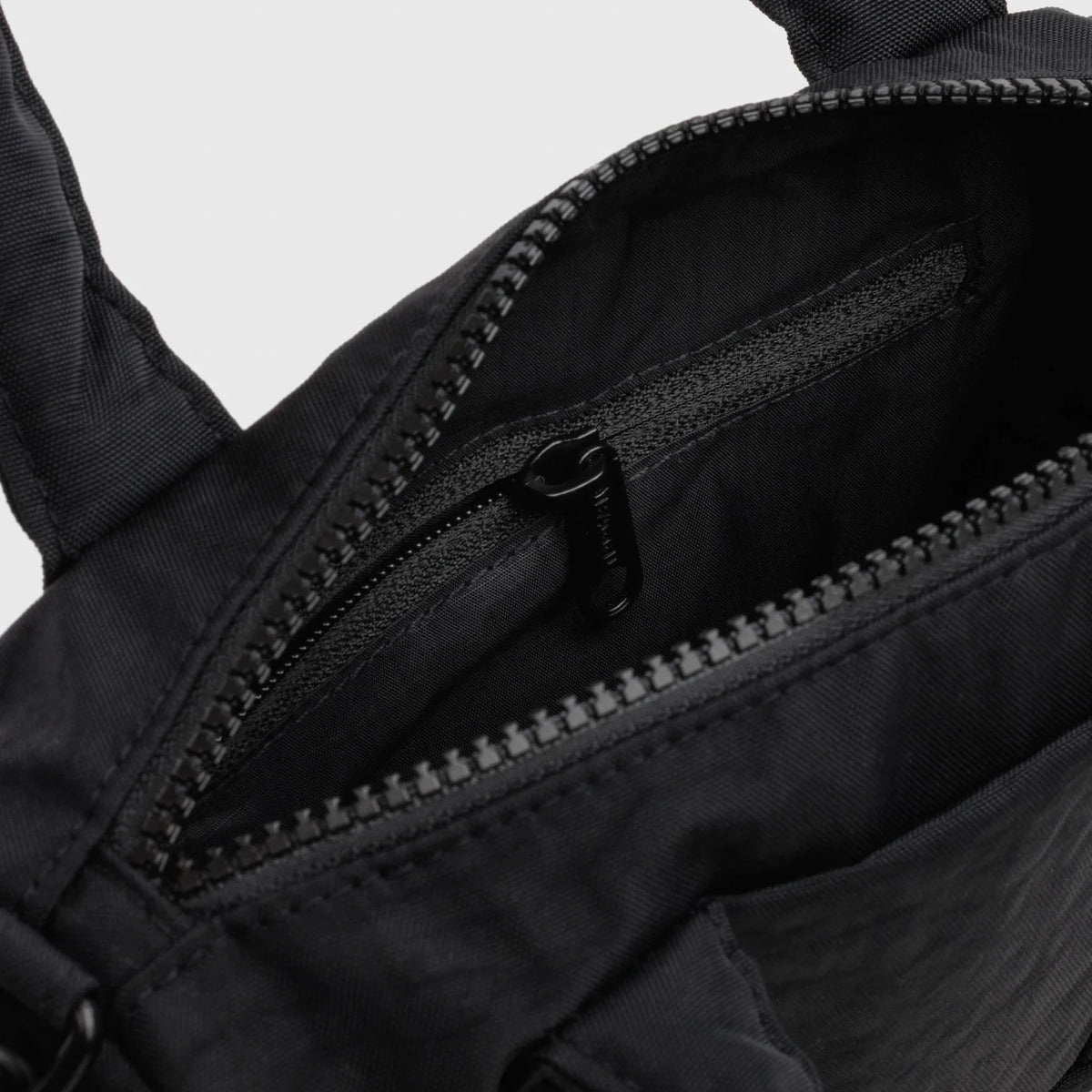Black nylon duffle bag interior close-up with zip track and lining