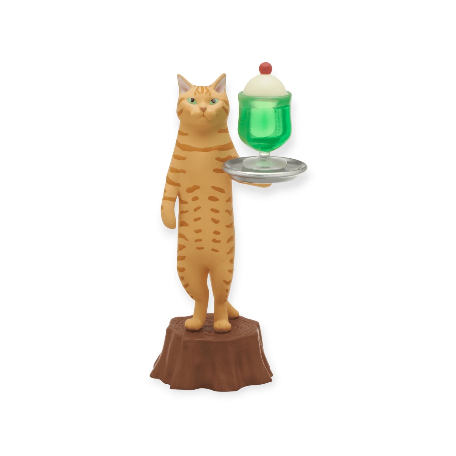 The Cat Cafe Waiter Blind Box by Kitan Club features a toy orange tabby cat waiter on a stump, balancing a tray with green dessert, whipped cream, and a cherry.