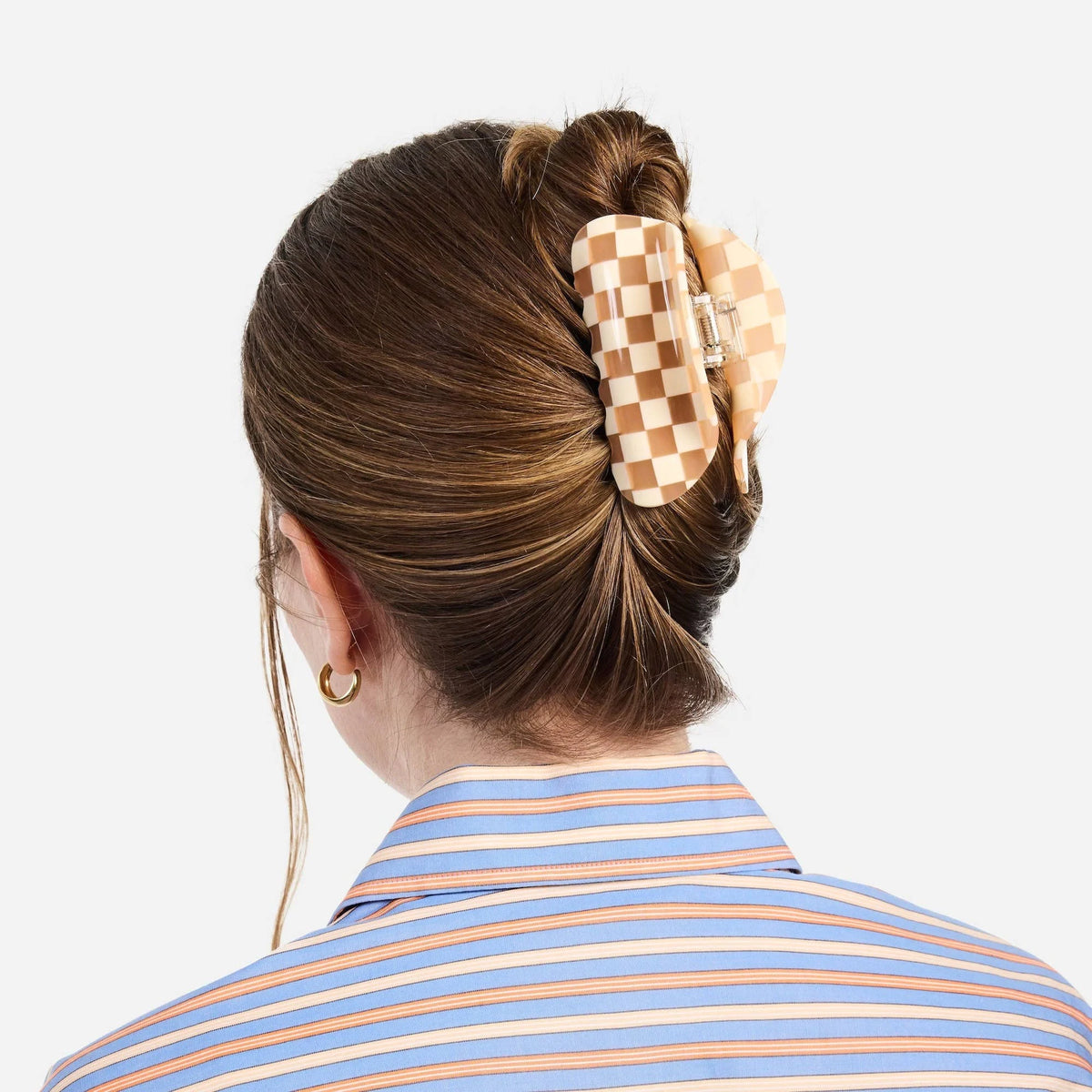 Peach checkered hair claw clip worn in a bun, silver clasp visible
