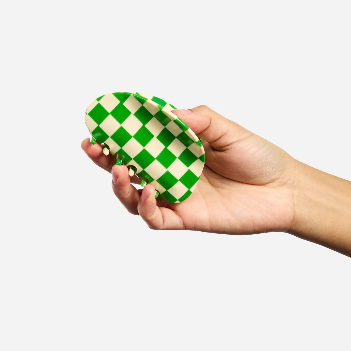 Green and white checkered claw clip in hand, domed back and teeth