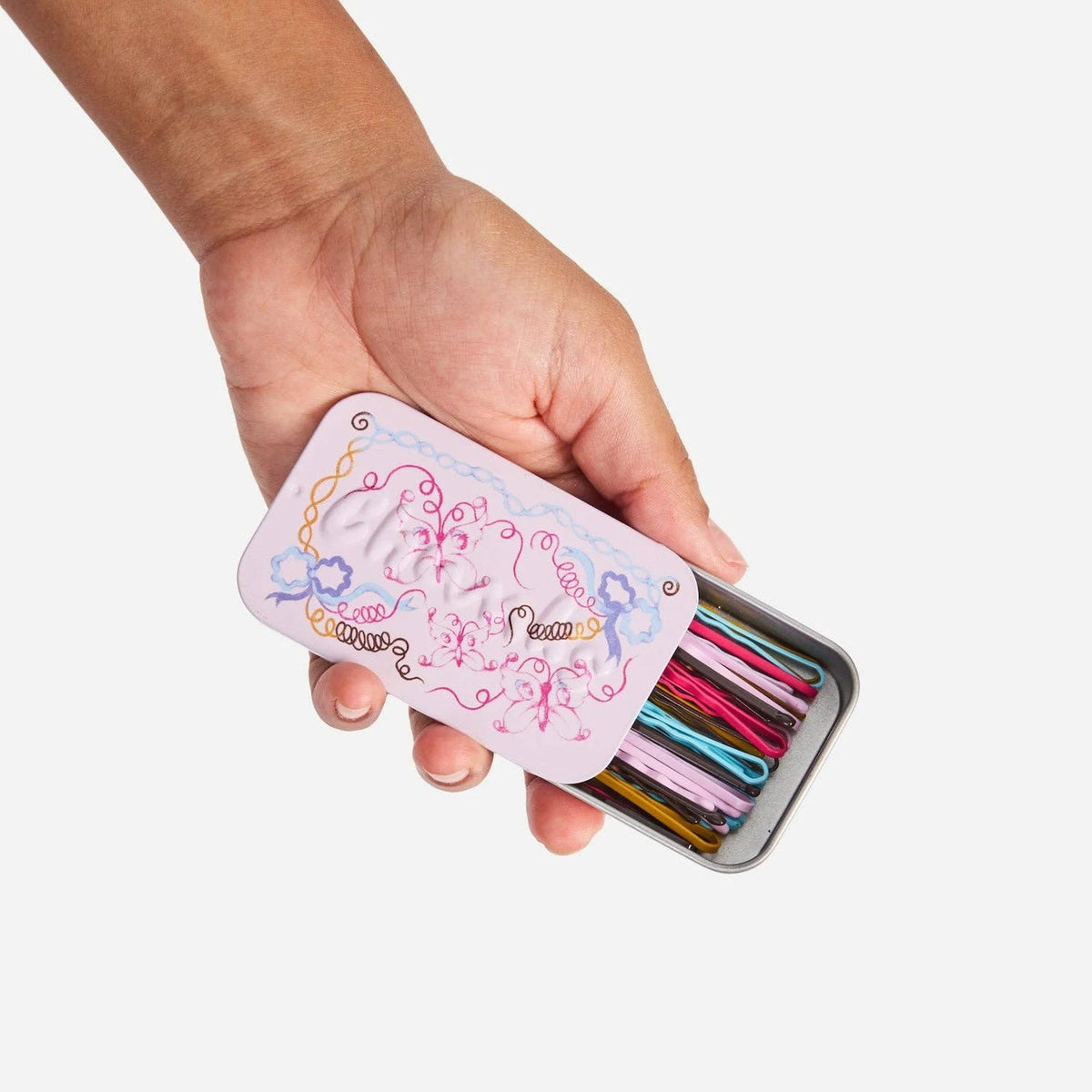 Bobby pins tin held in hand, showing multicolor pins through the open case