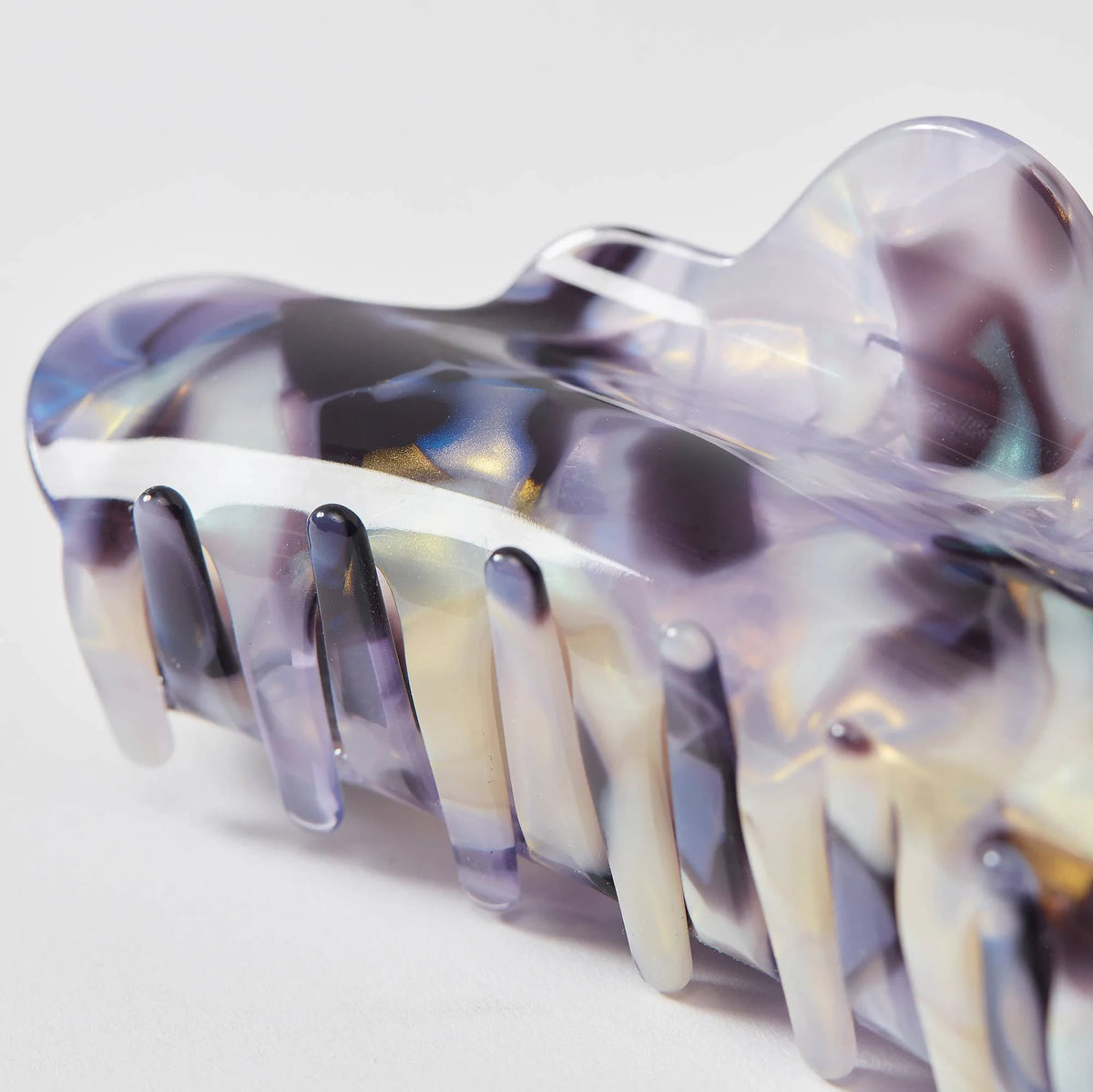 Large translucent claw clip with clear purple-and-blue swirls and long metal-like teeth.