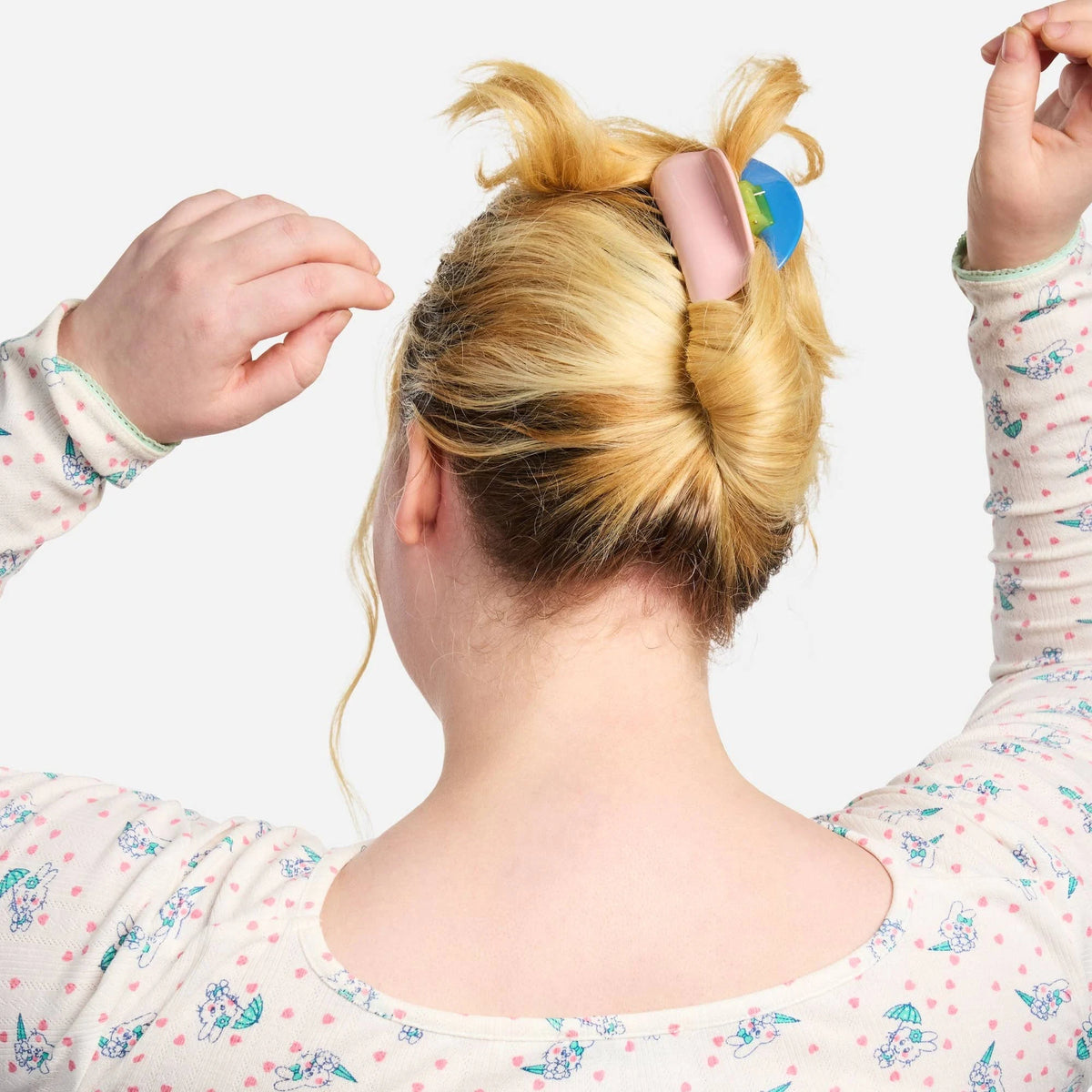Pink chunky claw clip securing a bun in blonde hair.