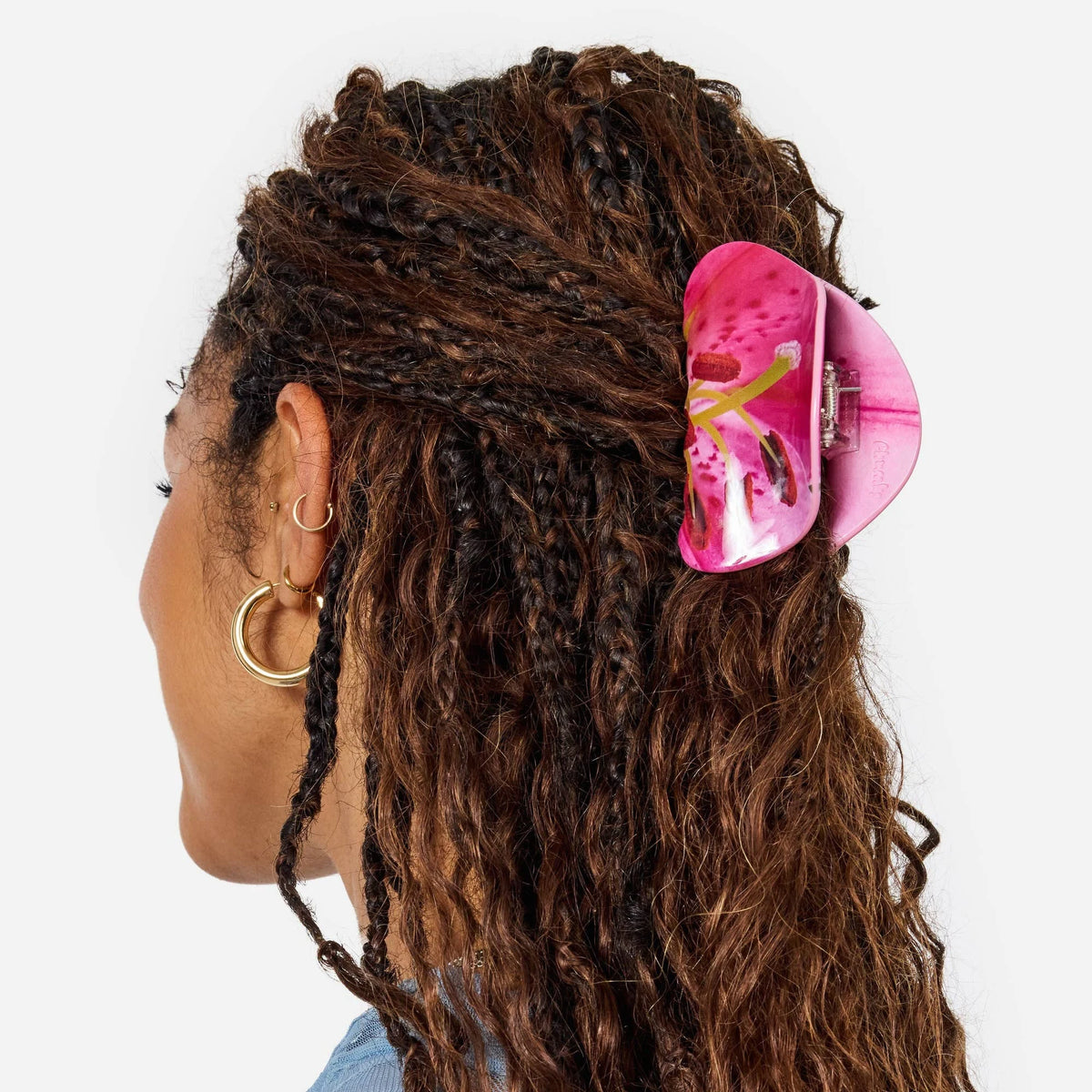 Pink lily-patterned claw clip on curly dark hair with gold-tone hardware