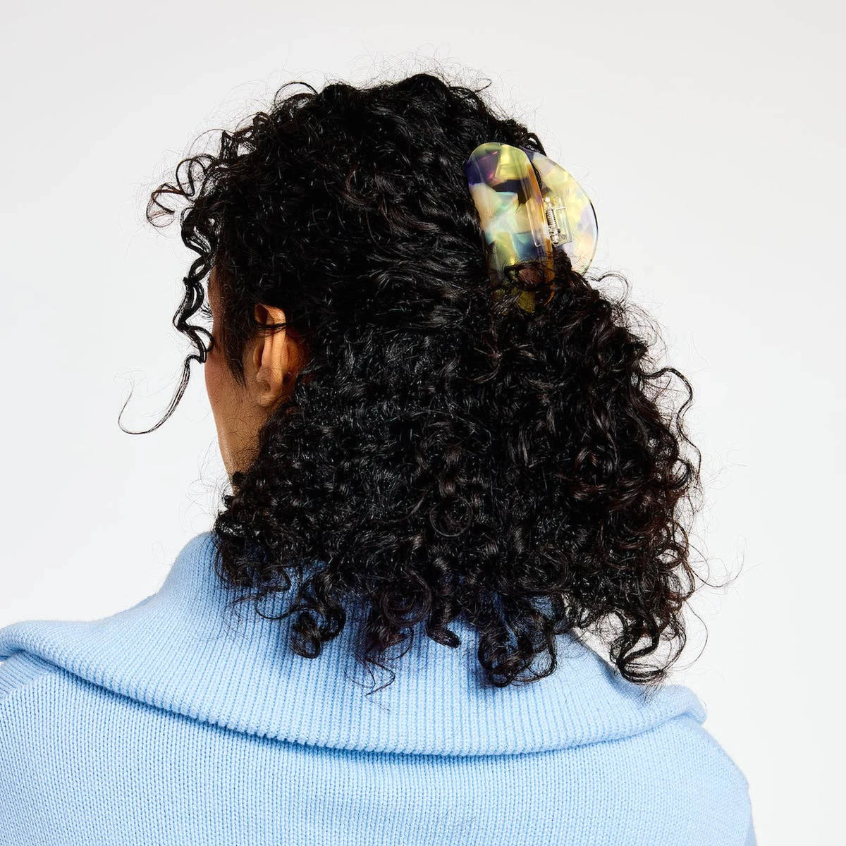 Curly hair secured with pastel translucent claw clip on the back