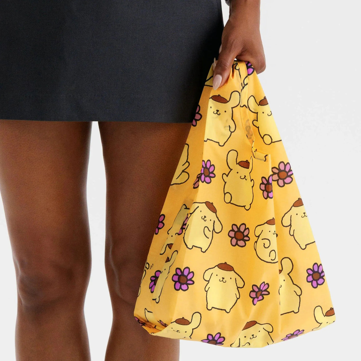 Baby Baggu tote bag held by a person, yellow with Pompompurin and purple flowers