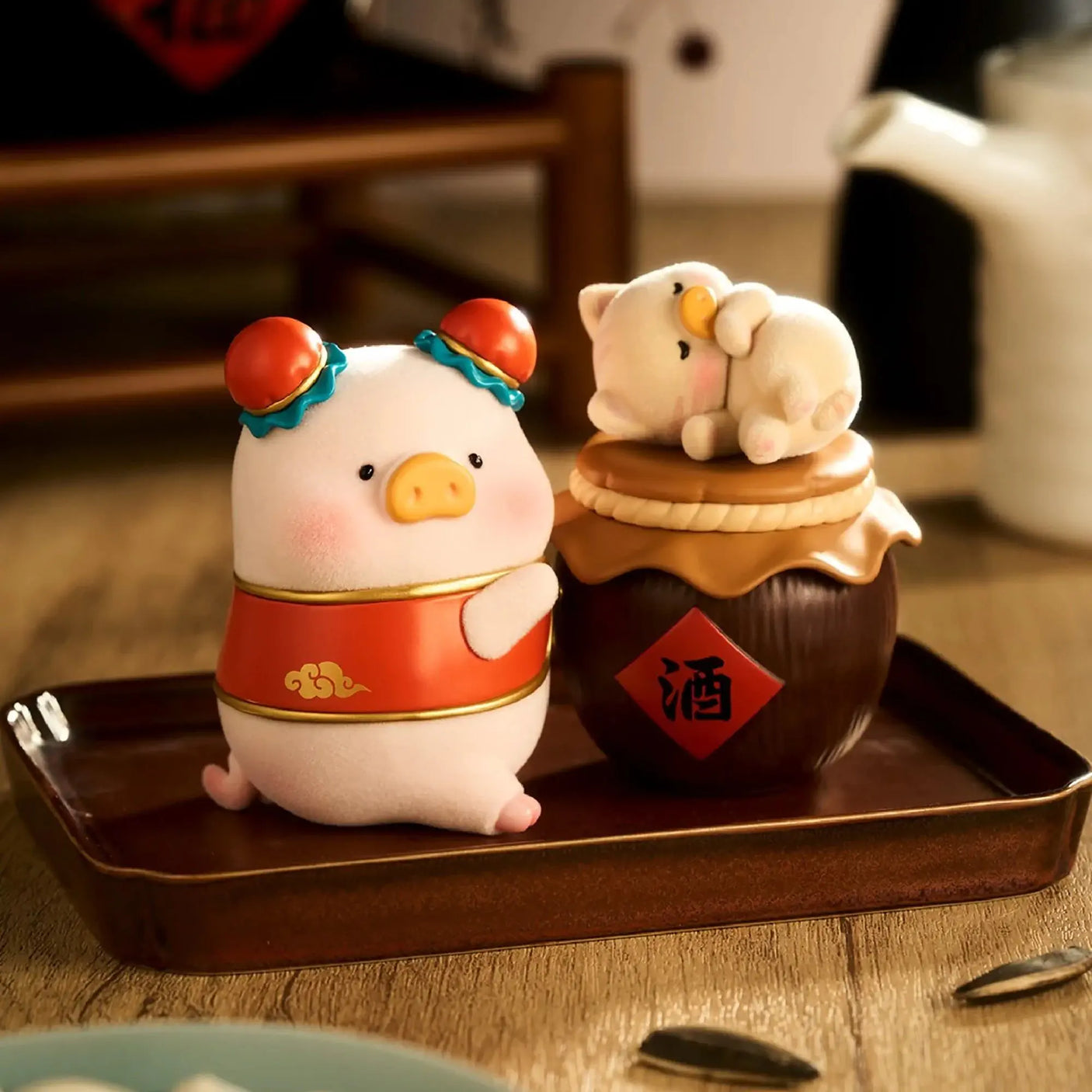 Piggy blind box figures on a tray: pig with red apron and bear-like figure on stand