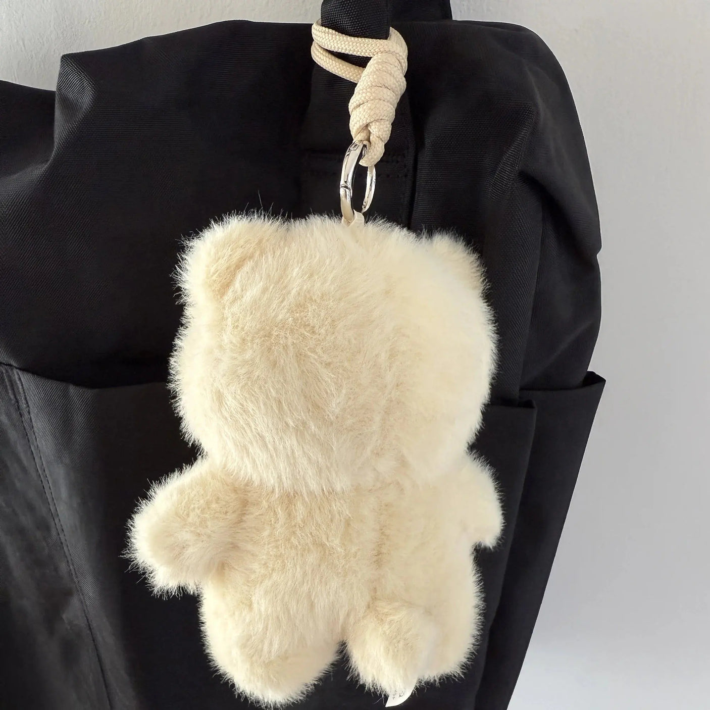 White plush pig keychain with loop clasp, hanging from black bag strap