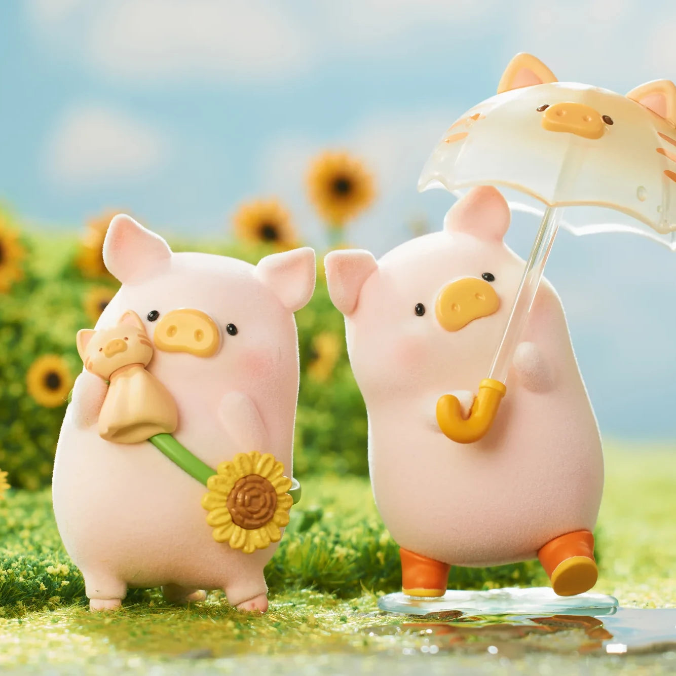 Two pink LuLu the Piggy figures one holding a sunflower and cat doll, the other with an umbrella in a sunflower field