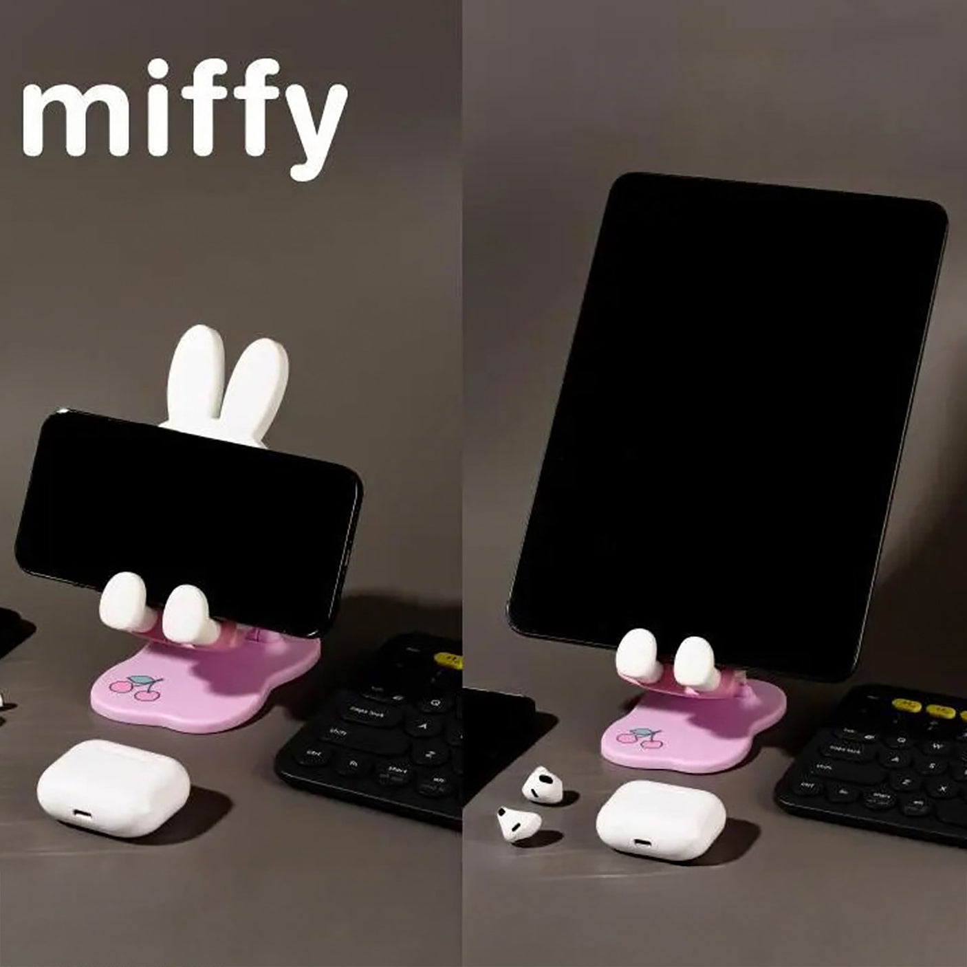 Pastel pink Miffy phone and tablet stand with white ears and hands holding devices on dark surface near wireless earbuds and keyboard