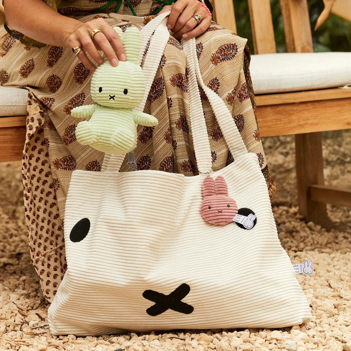 White striped corduroy rabbit keychain with metal ring, hanging from a bag