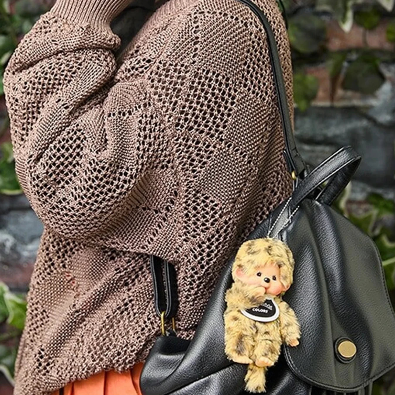 Leopard-pattern plush bag charm on a black handbag, with beaded chain