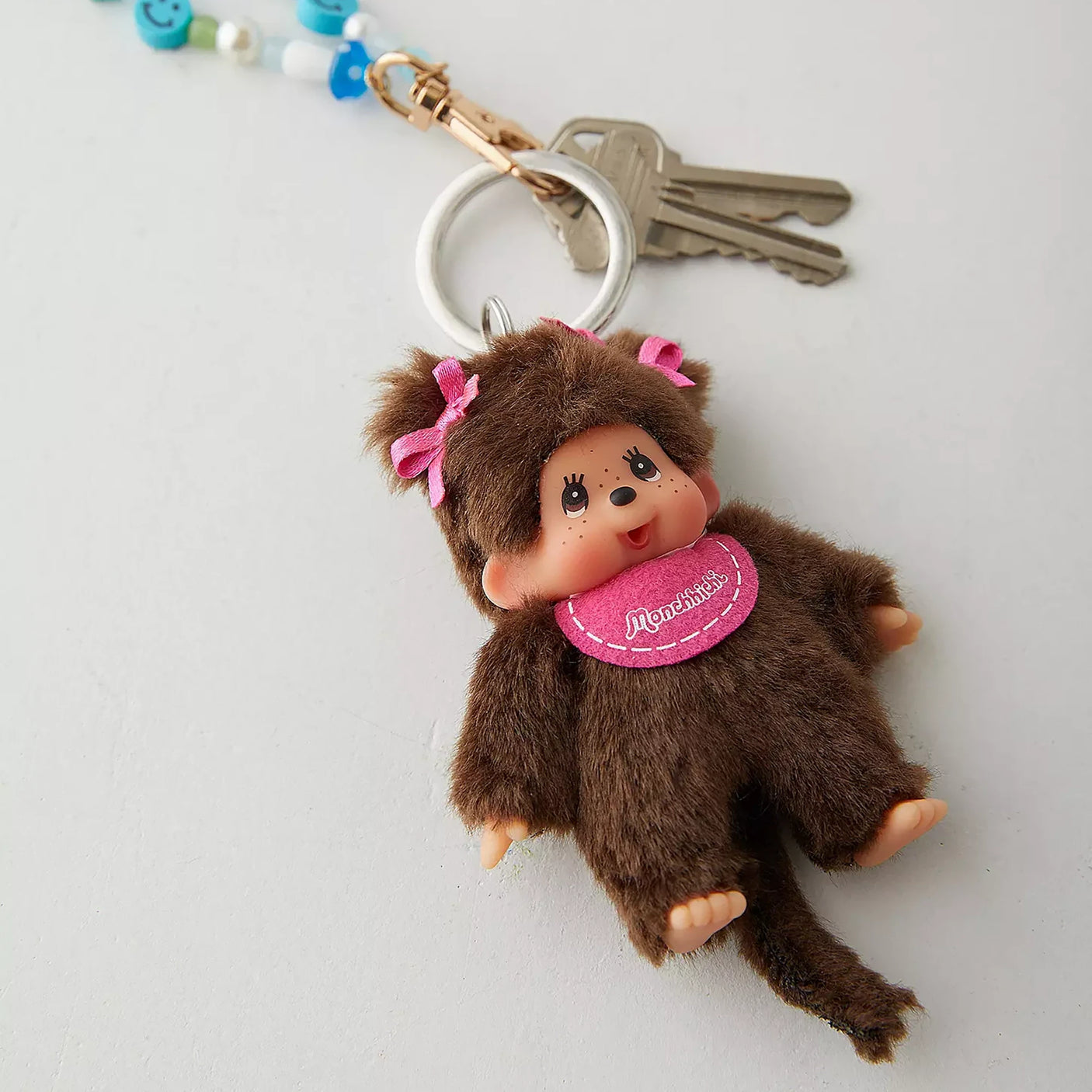 Dark brown plush girl keychain charm with pink bows and round pink badge