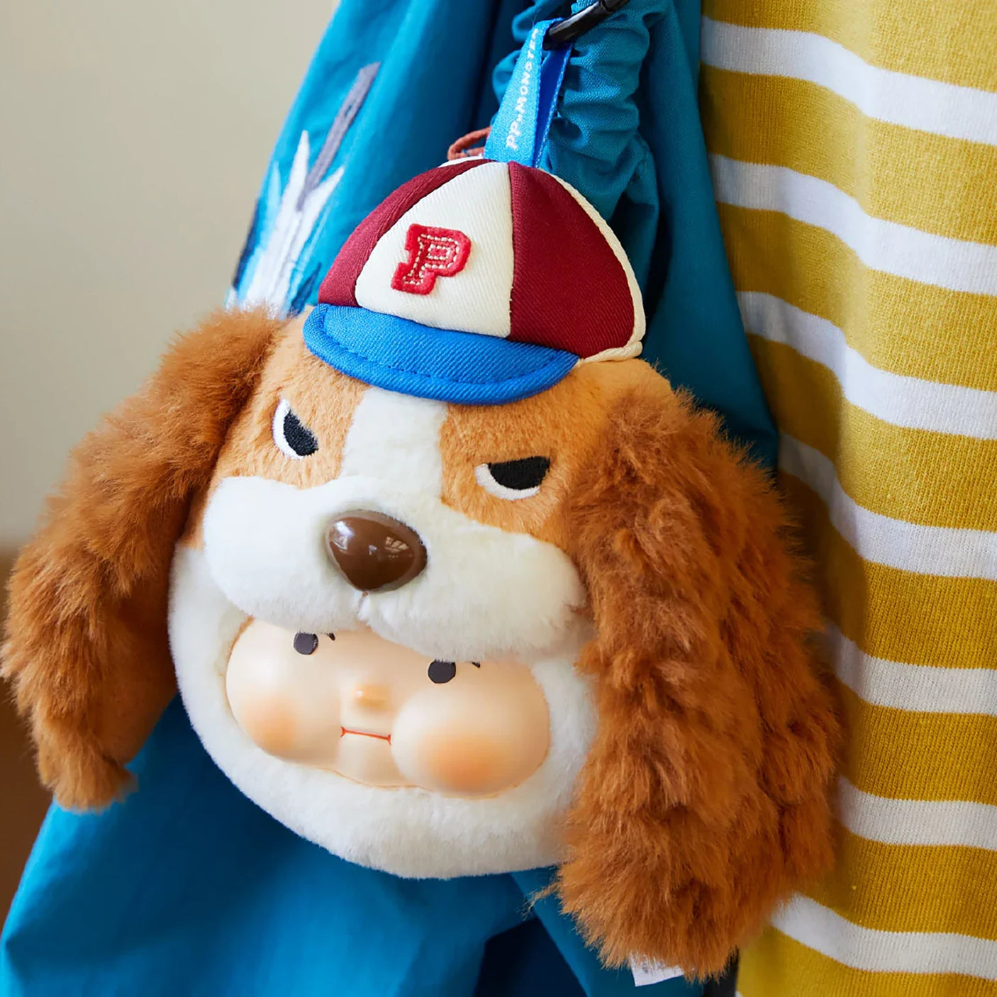Plush dog keychain with floppy ears and red-white-blue cap, brown and white face