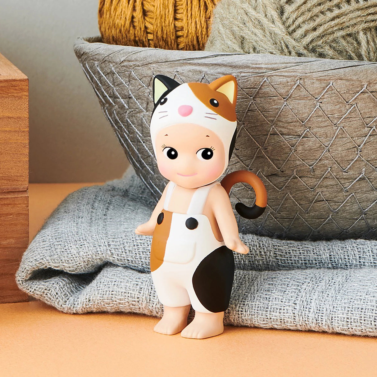 In the Sonny Angel Cat Life Series - Blind Box by Sonny Angel, a captivating figure dressed as a calico cat is playfully posed before a basket overflowing with yarn, perfectly embodying a sense of playful mischief. This limited edition item is an ideal addition for collectors and cat enthusiasts.