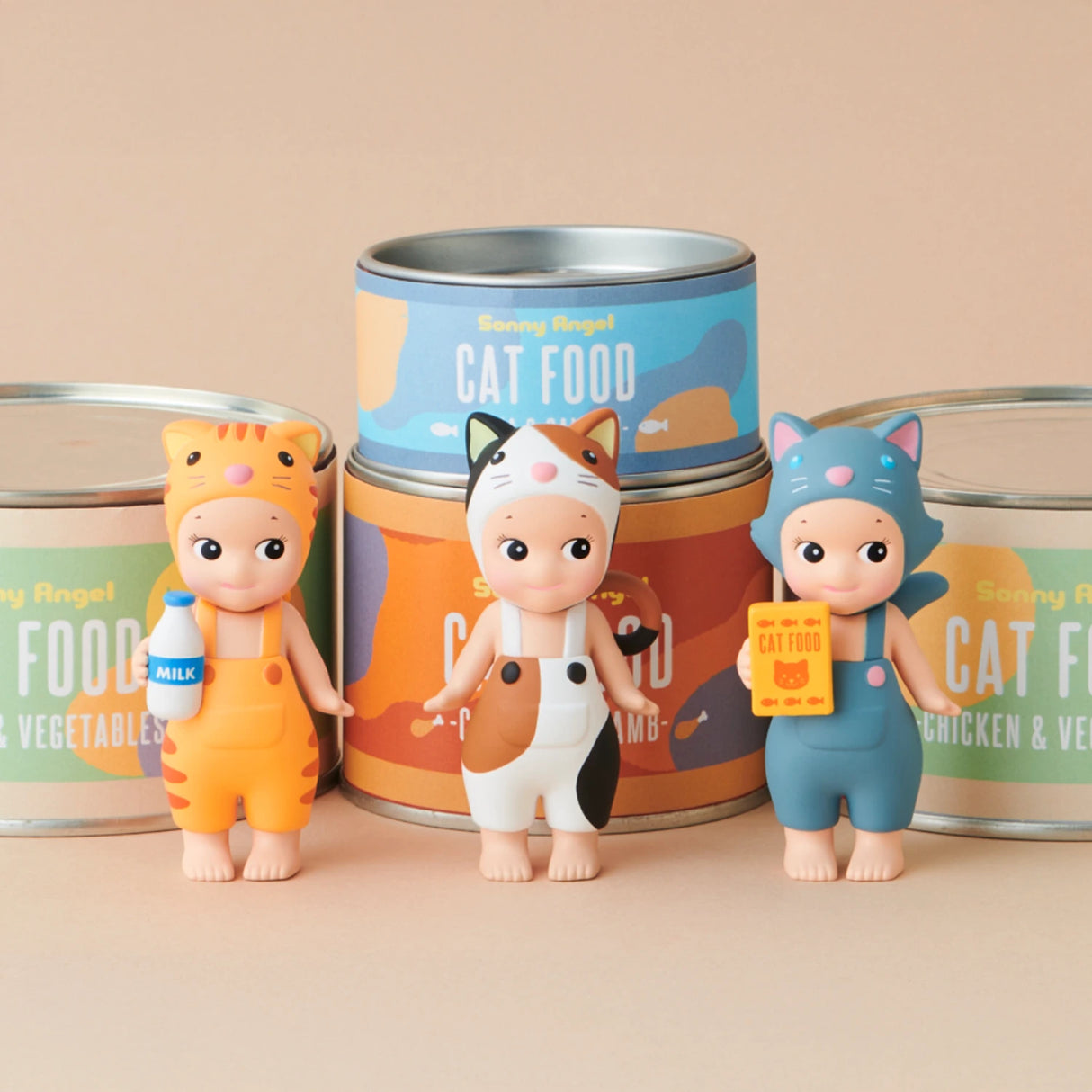 As part of the limited edition Sonny Angel Cat Life Series by Sonny Angel, three figurines disguised as cats pose before vibrant cat food cans, each grasping a themed object: a milk bottle, a fish, and a food box.