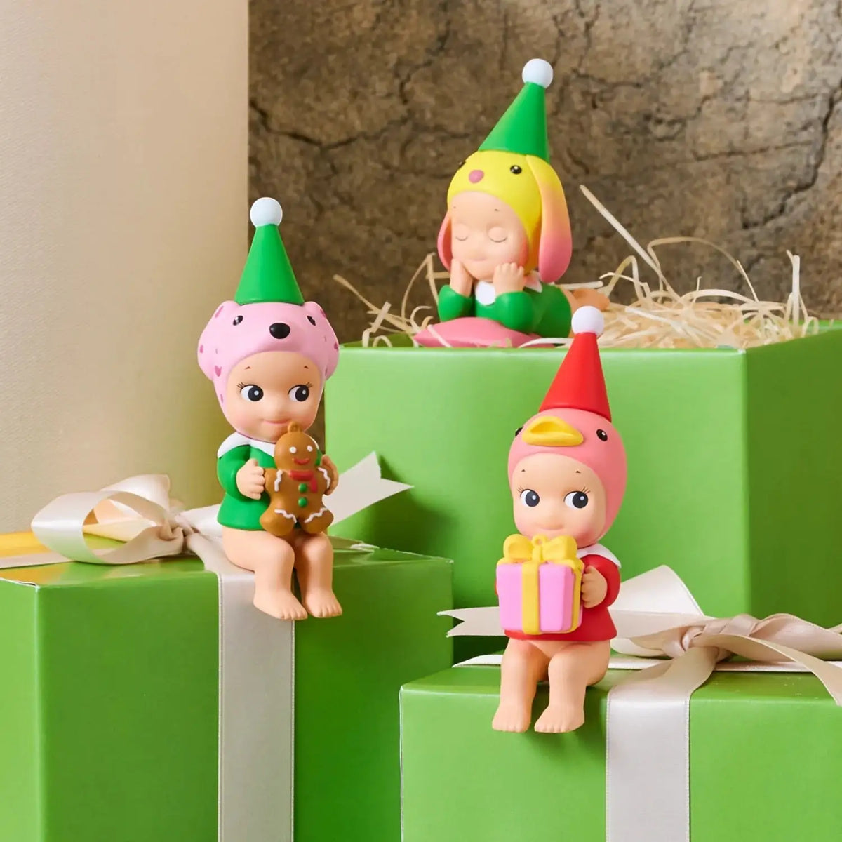Mini elf vinyl figures seated on stacked gift boxes, holding small gifts