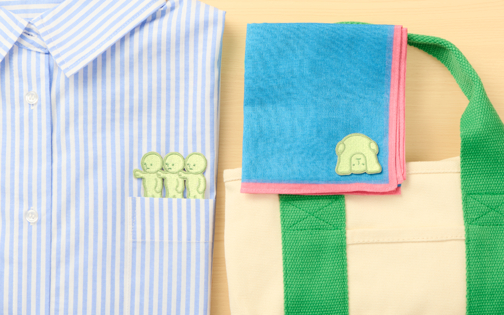 Green embroidered Smiski peeking 2 sticker on folded fabric