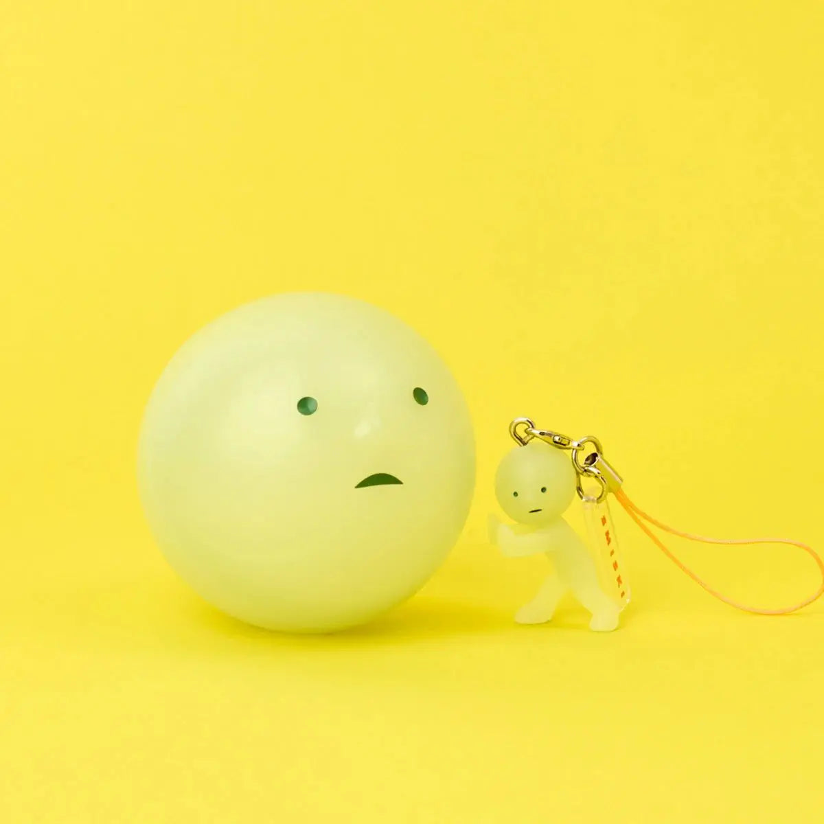 Smiski pale yellow strap keychain charm with small figure and gold clip