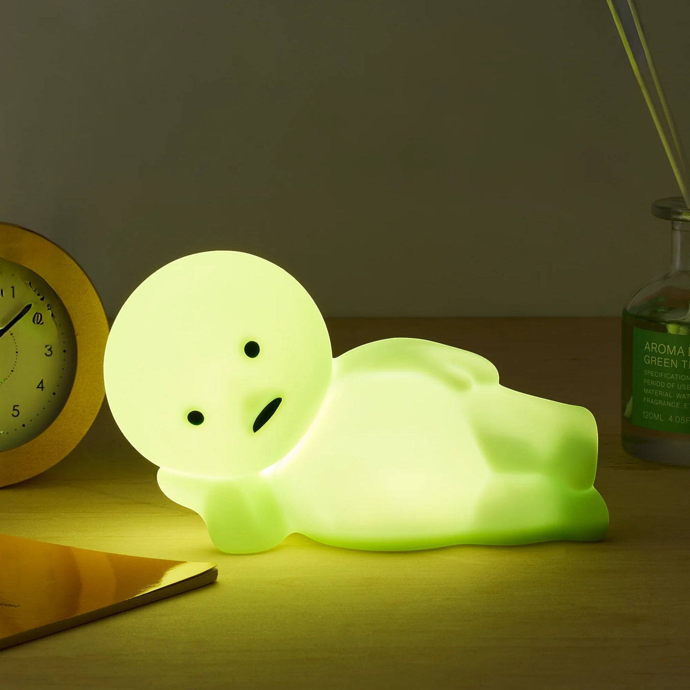 Smiski Touch Light lounging figure, light green, glowing on a tabletop