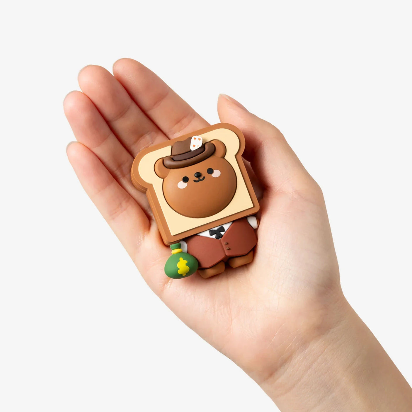 Hand holding a Wild West bear figure keychain with a brown hat and small green accessory