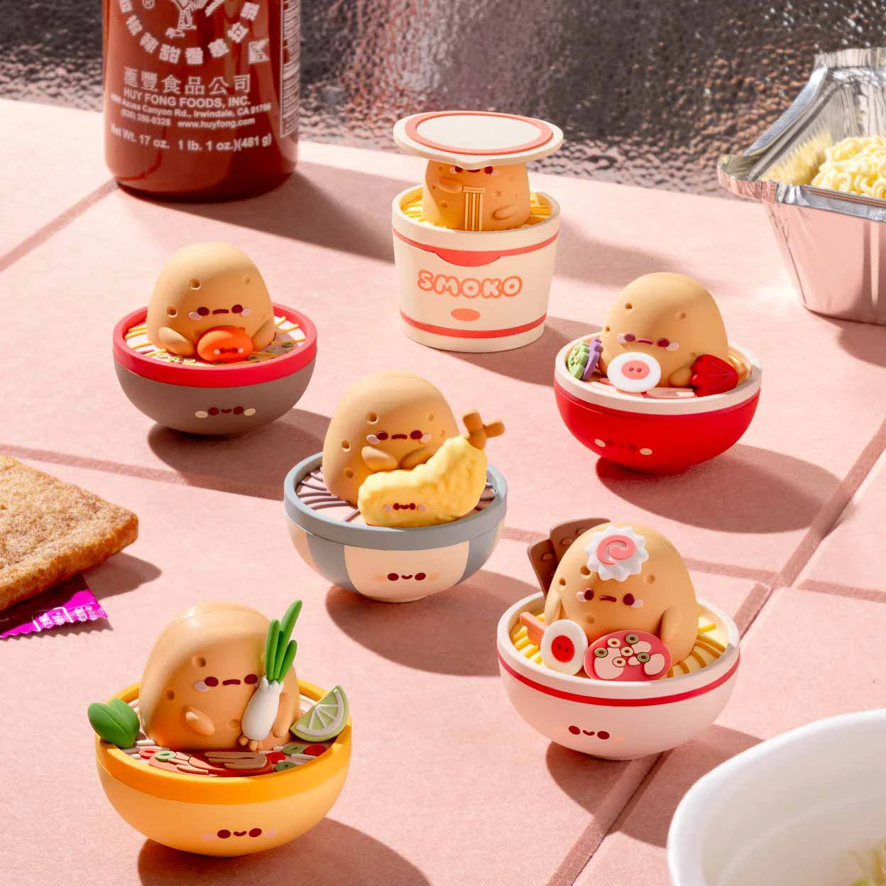 Six Smoko Tayto Ramen vinyl figures styled as various ramen dishes with cute facial expressions on a table.