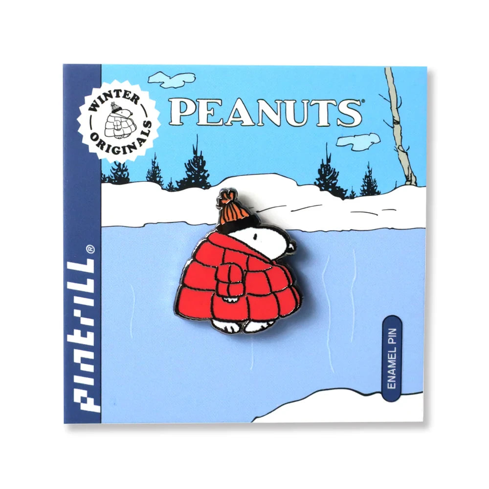 The Snoopy Puffer Jacket Pin by Snoopy shows Snoopy in a red winter coat and hat, presented on a snowy, Peanuts-themed backing card with wintry trees.