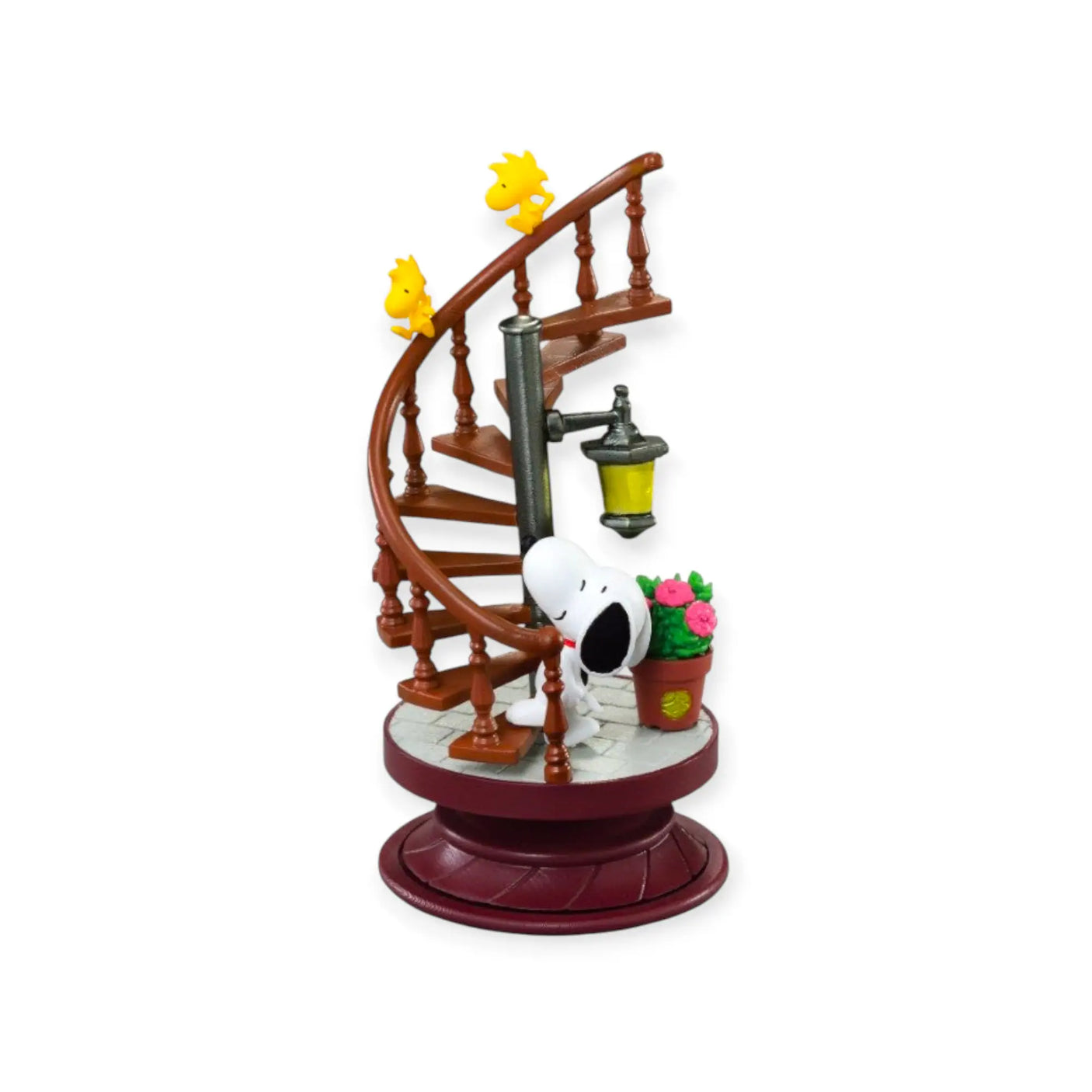Snoopy spiral diorama figure on a maroon base with wooden spiral stairs and small plants