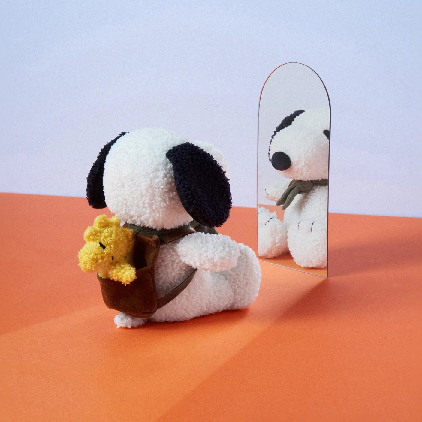 Plush Snoopy backpack with yellow Woodstock charm, brown strap, with mirror reflection