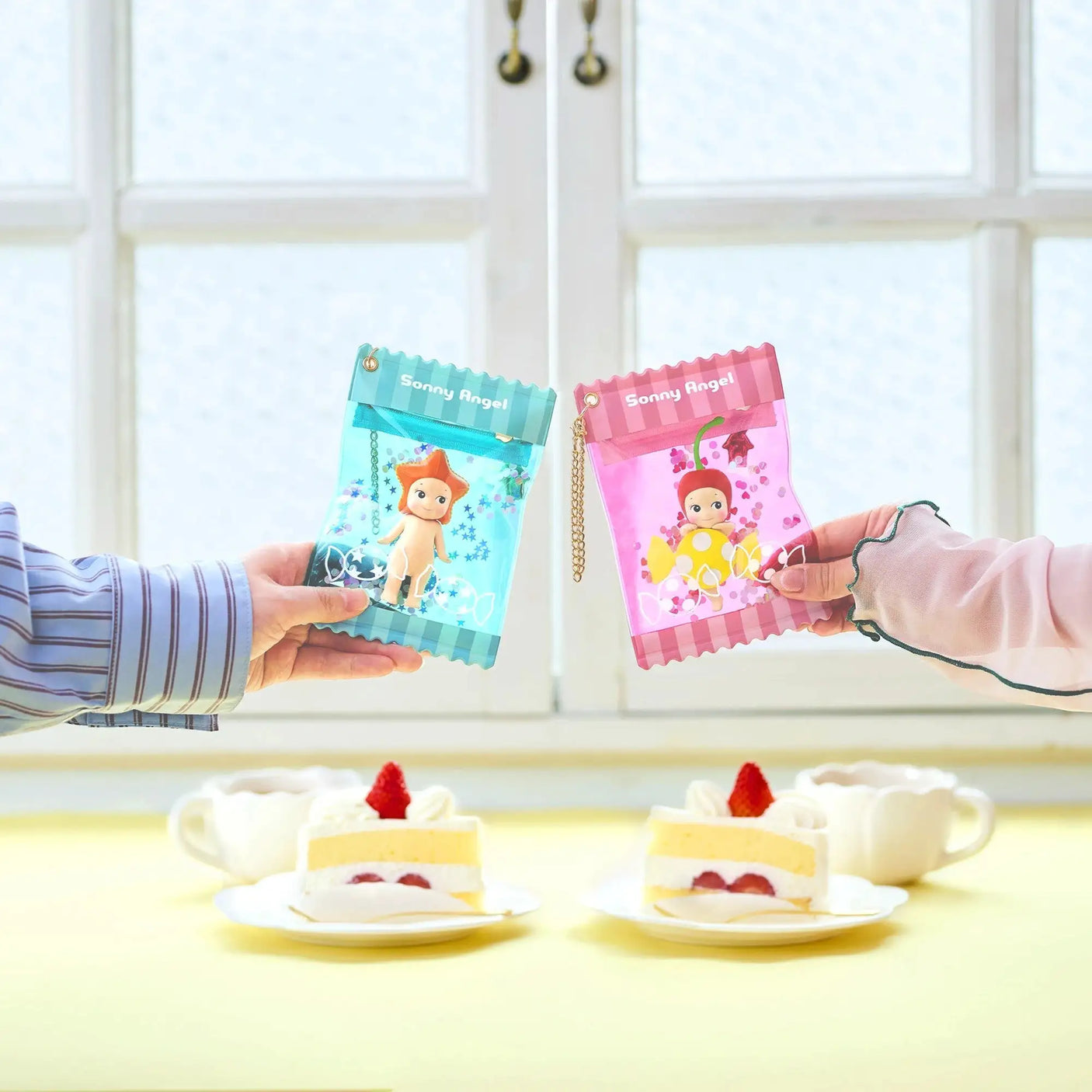Blue mini candy pouch case with chain held next to pink case