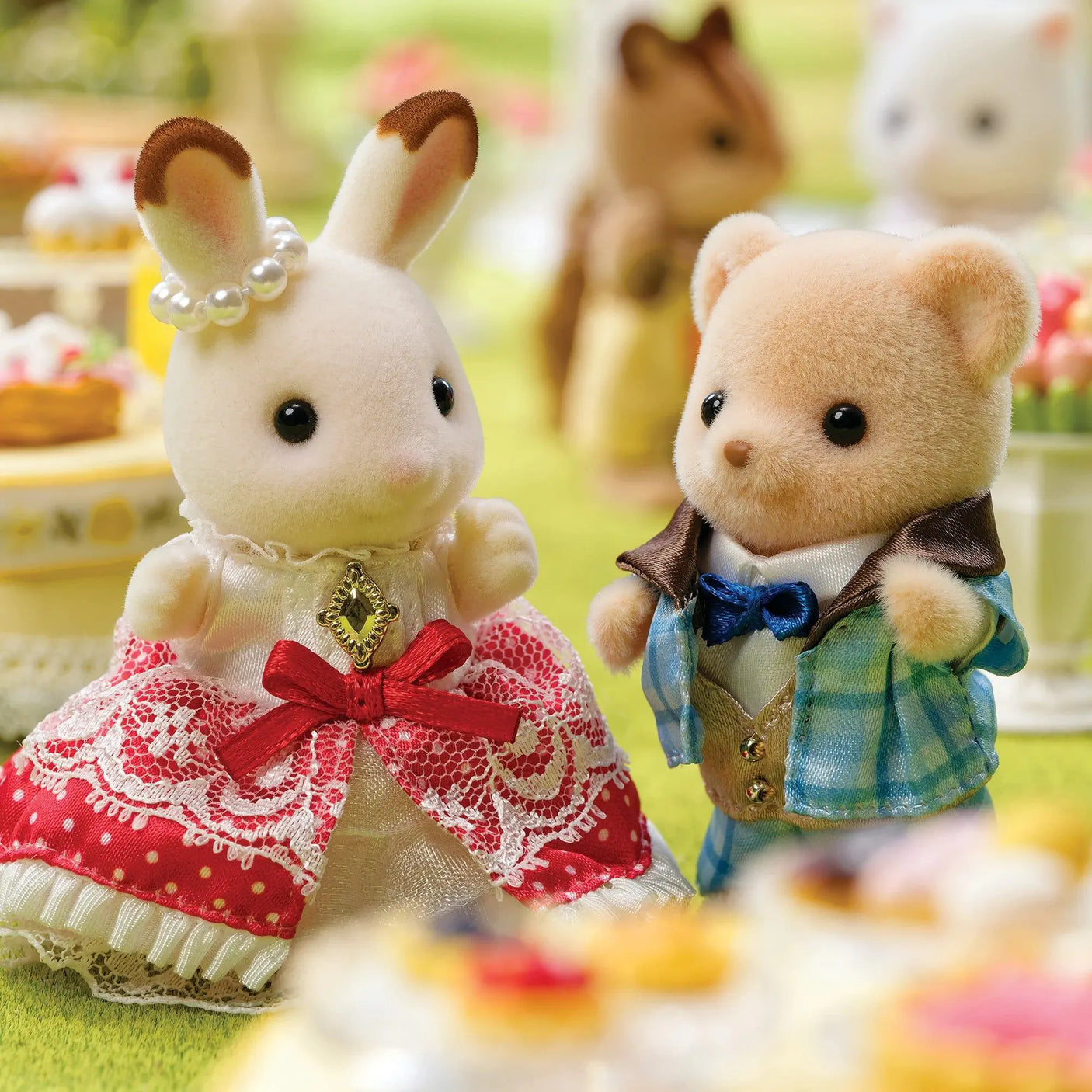 Close-up of plush bunny in red dress and plush bear in blue plaid outfit with bow