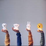 Four hands are holding nightlights shaped like animals from the Miffy collection, featuring a polar bear, a brown bear, a rabbit, and the Lion Miffy Night Light (15cm), all set against a plain background.