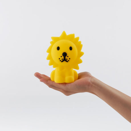 A Lion Miffy Night Light (15cm) from the Miffy brand, featuring a yellow lion shape with black details from the Miffy and Friends Light Series, is held in the palm of a hand against a plain white background.