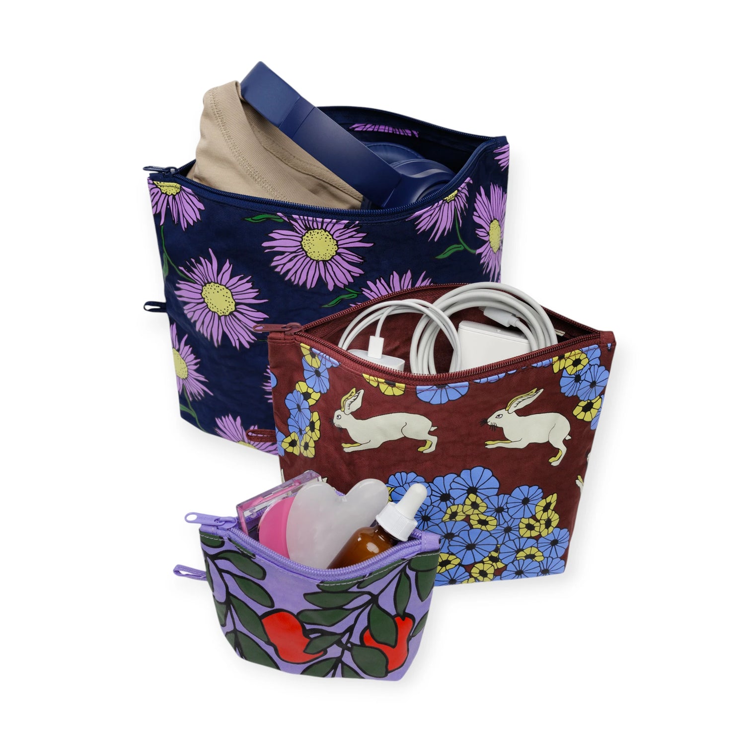 Set of three colorful Baggu Go pouches with floral and rabbit prints, filled with everyday essentials and tech items.