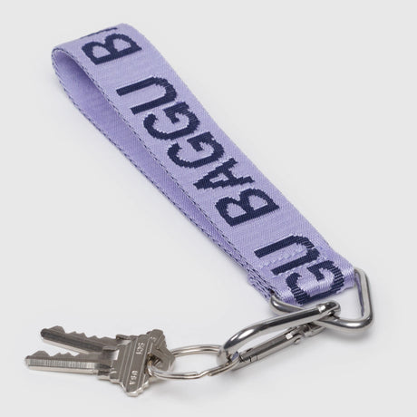 The Baggu Logo Keychain - Dusty Lilac by Baggu features dark branding, comes with a metal carabiner keyring, and holds three silver keys.