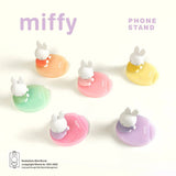 Assorted pastel bunny phone stands with white figurines on orange, pink, green, and purple bases