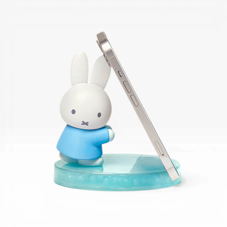 Blue circular phone stand base with white bunny figurine and silver phone holder