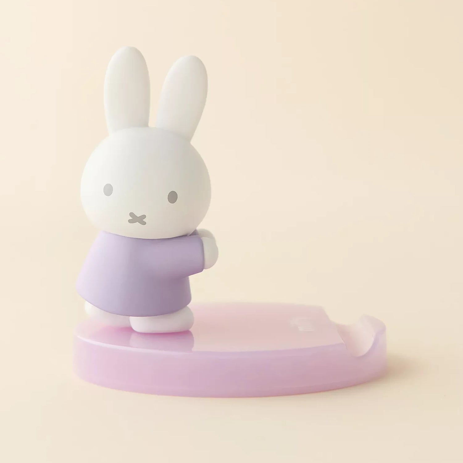 White bunny figurine with lavender shirt on light pink base phone stand, side view