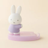 White bunny figurine with lavender shirt on light pink base phone stand, side view